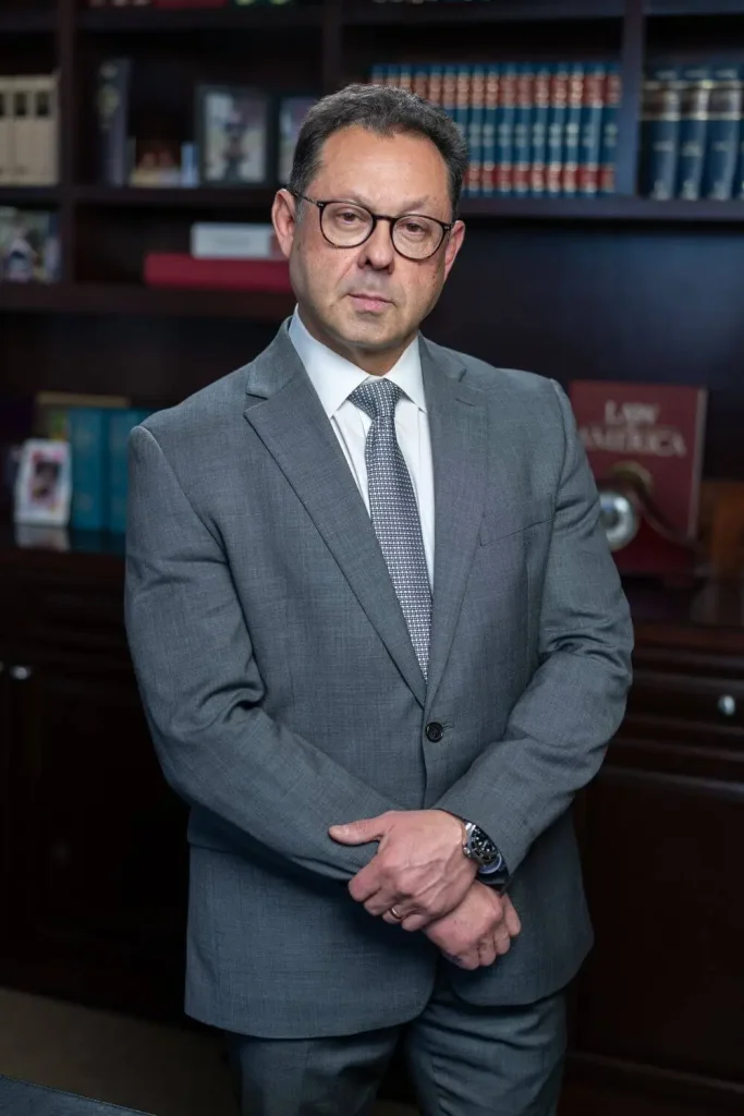 Dmitry Y. Gurovich in a blue suit standing in his office, smiling as he prepares to meet a new client.